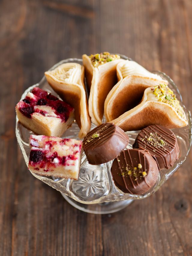 Glasfat på fot med atayef, bakverk och cheesecakebitar med bär.