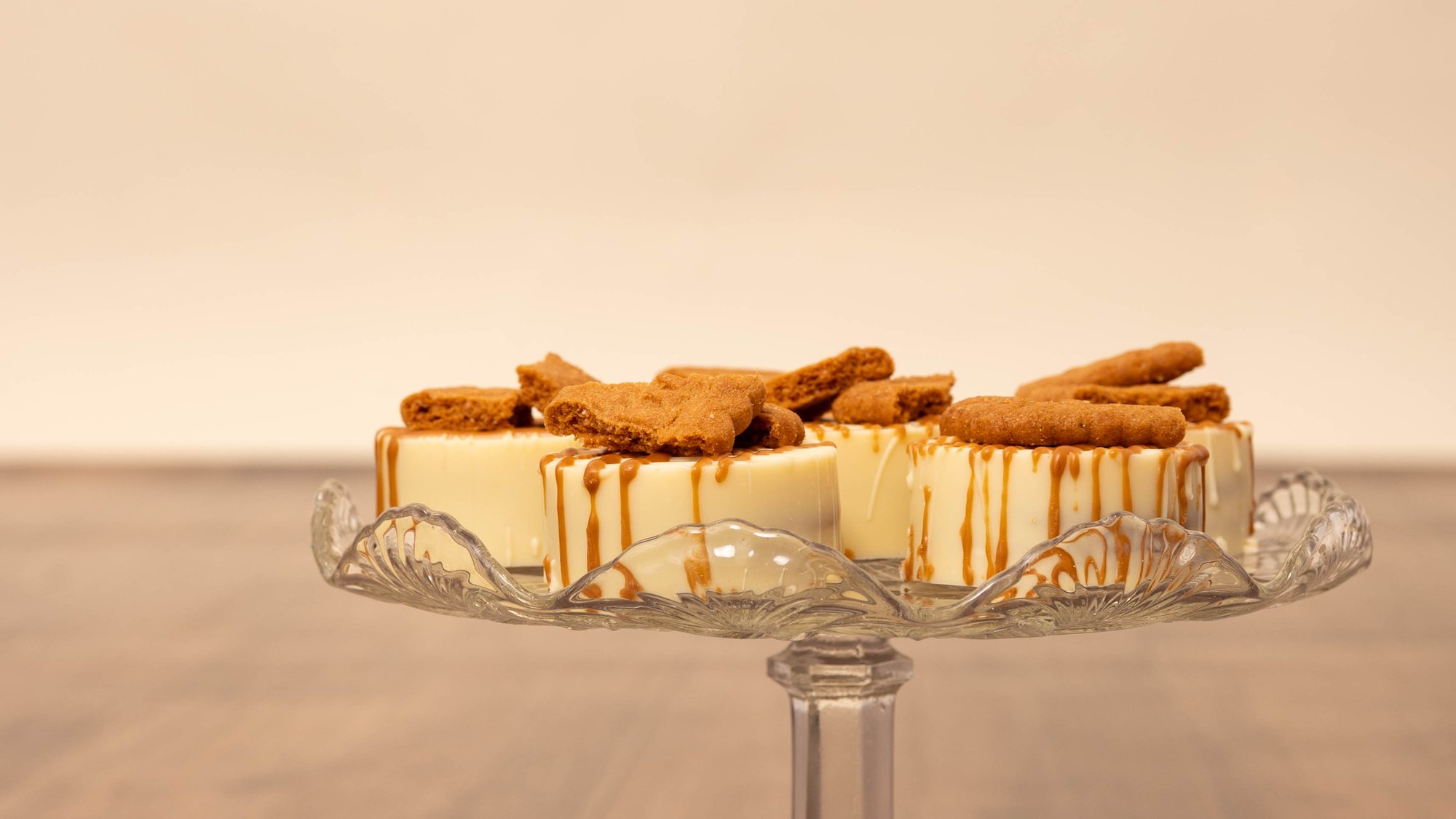 Glasfat med cheesecakebitar toppade med biscoff, bredvid ett glas bubbel.